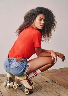 a woman sitting on top of a wooden floor next to a skateboard