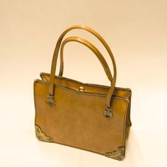 This cute 1970's bag is flawlessly crafted from beige leather in a timeless shape. This style has a lightly structured frame, vintage metal corners and silk lining interior that comfortably holds your everyday essentials.  This item's measurements are: Height 16cm Width 22cm Depth 10cm Visit our instagram @forteandco for the first sight of our finds and early offers! Retro Brown Box Bag For Everyday, Formal Tote Satchel With Brass Hardware, Formal Satchel With Brass Hardware, Formal Satchel With Brass Hardware And Tote Shape, Formal Satchel Tote With Brass Hardware, Retro Satchel With Gold-tone Hardware For Daily Use, Vintage Square Box Bag, Vintage Shoulder Box Bag For Daily Use, Classic Gold Satchel With Brass Hardware