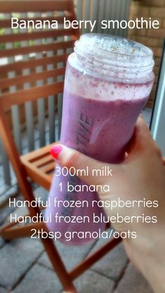 a person holding up a smoothie in front of a wooden chair with the words banana berry smoothie on it