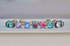 "A stunning new bracelet made using Swarovski crystal. The crystals are 8mm in size and range in color from tanzanite shimmer, violet, rose Glacier, and Light Turquoise. There are also small links featuring opaque turquoise jewels, with bright fuchsia pink centers. All stones are prong set into an antique brass bracelet setting. Bracelet closes with a lobster clasp, and will adjust to fit wrist sizes 6.5\" and up. LIMITED SUPPLY. ** Nickel and lead free" Pastel Violet, Candy Bracelet, Bracelet Tennis, New Bracelet, Violet Rose, Swarovski Crystal Jewelry, Brass Bracelet, Pink Purple Blue, Rose Pastel