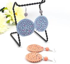 two crocheted earrings with dangling hooks and beads are shown on a white background