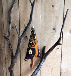 an ornament hanging from a tree branch on a wooden wall next to some branches