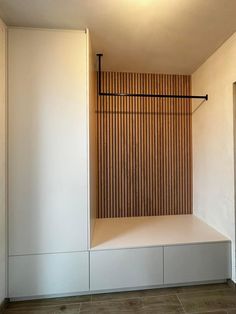 an empty white room with wooden slats on the wall and flooring in front of it