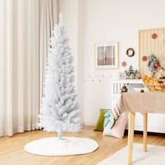 a white christmas tree sitting on top of a wooden floor next to a dining room table