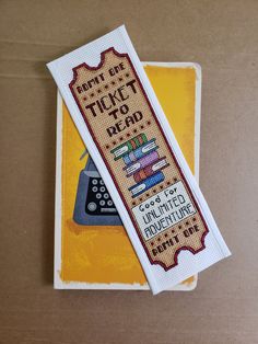 two cross - stitch bookmarks on top of each other, one with a typewriter