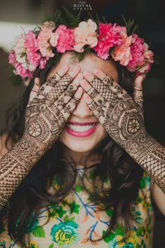 a woman holding her hands up to her face with flowers on top of her head