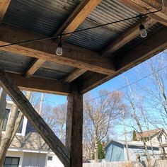 an outdoor covered patio with lights hanging from it's ceiling and trees in the background