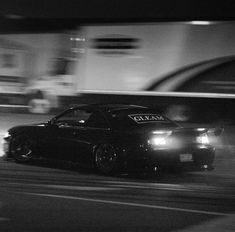 a black car driving down a street at night