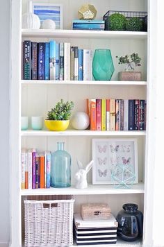 a bookshelf filled with lots of different types of books and vases on top of it