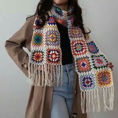 a woman is wearing a scarf with crochet on it and standing in front of a white wall