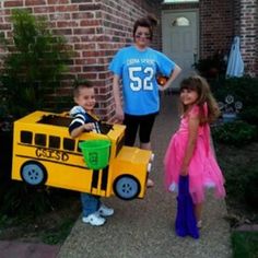 two children and an adult standing in front of a house with a school bus costume on