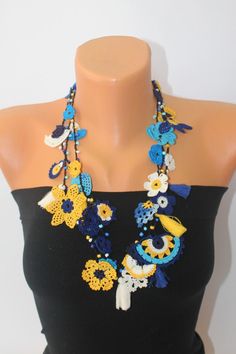 a woman wearing a black top with blue and yellow beaded necklace on her neck