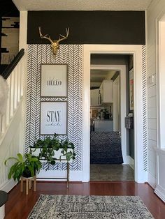 the entryway is decorated with black and white wallpaper, an antler's head on the wall