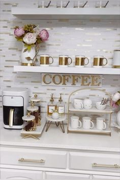 a white counter topped with lots of cups and saucers next to a shelf filled with coffee mugs