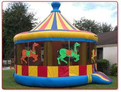 an inflatable bouncer with horses on it sitting in the grass next to a house