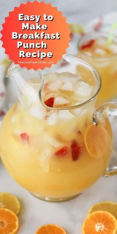 an orange drink in a pitcher with ice and strawberries on the rim next to sliced oranges