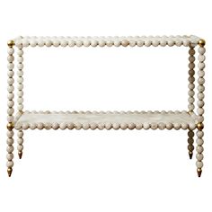 a white and gold shelf with beads on the bottom, one shelf is holding two shelves