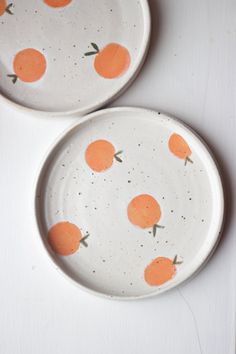 two plates with oranges painted on them