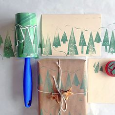 wrapping paper, scissors and tape are sitting on top of each other next to christmas trees