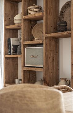 a living room with wooden shelves filled with baskets and books on top of each shelf