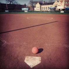 an orange ball sitting on top of a baseball field in front of a white house