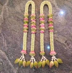 two necklaces made out of flowers and beads on a marble counter top, with one bead in the middle