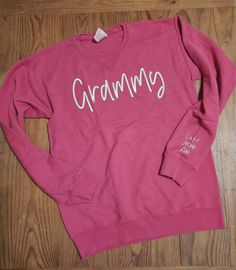 "This shirt is perfect for any Grandma, Nana, or Grammy.  Sweatshirt is 7.2 oz., 80% reclaimed US cotton, 20% recycled poly, 100% ringspun cotton face. Design is machine embroidered with premium embroidery thread. Full color chart available in the listing photos. ------------------------------- Embroidery instructions: 1. Name for full chest 2. Names for sleeve 3. Sleeve to embroider on (Right or Left) 4. Embroidery thread color (white or black are default, depending on the color of the sweatshi Cotton Crew Top With Embroidered Text, Pink Crew Cotton Top, Pink Cotton Crew Top, Relaxed Fit Long Sleeve Tops With Lettering, Pink Long Sleeve Sweatshirt With Name Print, Fitted Cotton Crew Neck Sweatshirt, Winter Cotton Top With Name Print, Fitted Long Sleeve Top With Name Print, Cotton Top With Name Print For Winter