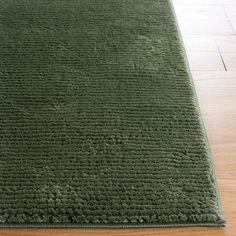 a green rug is laying on the floor in front of a wood flooring area