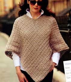 a woman is walking down the street wearing a crocheted ponchy sweater