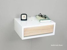 a white shelf with a clock, book and glasses on it