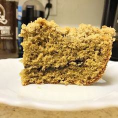 a close up of a piece of cake on a plate with coffee in the background