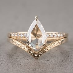 an engagement ring with a pear shaped cut diamond in the center and side stones on each band