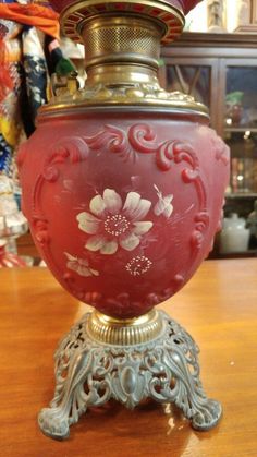 a red vase sitting on top of a wooden table