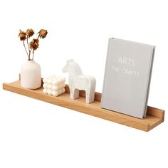 a wooden shelf with two white vases and a book on it that says arts the crafts