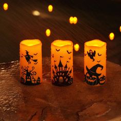 three lit candles sitting on top of a wooden table covered in halloween decorations and pumpkins