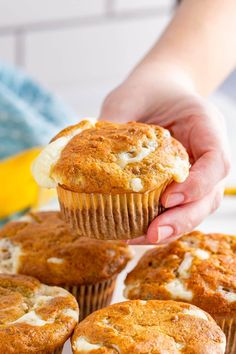 a person holding a muffin in front of some other muffins