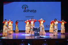 a group of women performing on stage in front of a large screen with adhata logo