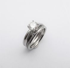 an engagement ring with two bands and a diamond in the center on a white background