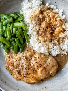 a white plate topped with rice and meat covered in gravy next to green beans