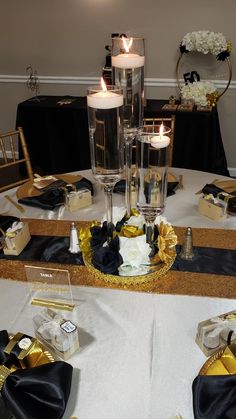 the table is set with black and gold napkins, candles, and gift boxes