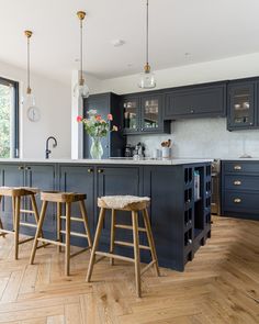 a kitchen with two stools in front of the island and an open floor plan