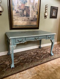 a blue table sitting on top of a carpeted floor next to a framed painting