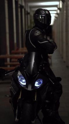 a person on a motorcycle with their arms crossed and headlight turned on in the dark