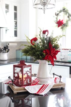 a christmas centerpiece with poinsettis and greenery on a kitchen counter