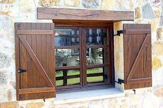 an open window with wooden shutters in front of a stone wall and green grass