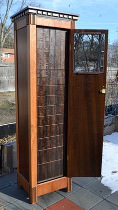 a tall wooden cabinet sitting on top of a sidewalk