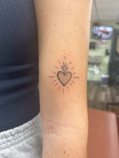 a woman with a small tattoo on her arm that has a heart in the center