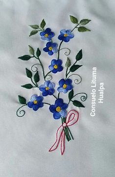 blue flowers with green leaves and red ribbon on white linens that have been embroidered onto