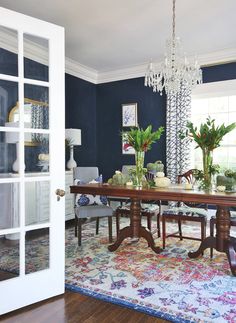 a dining room with blue walls and white trim on the door, chandelier hanging from the ceiling