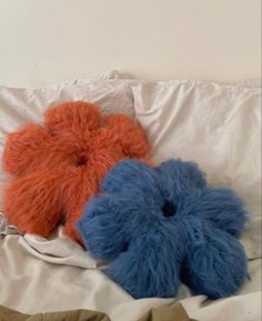 two blue and orange teddy bears laying on top of a white bedding with an unmade comforter